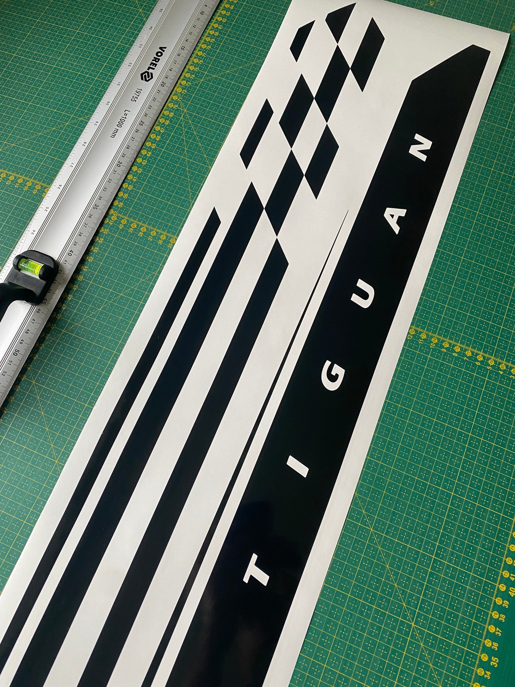 A vinyl decal with a geometric pattern and the word 'TIGUAN' displayed on a surface, likely a car part.