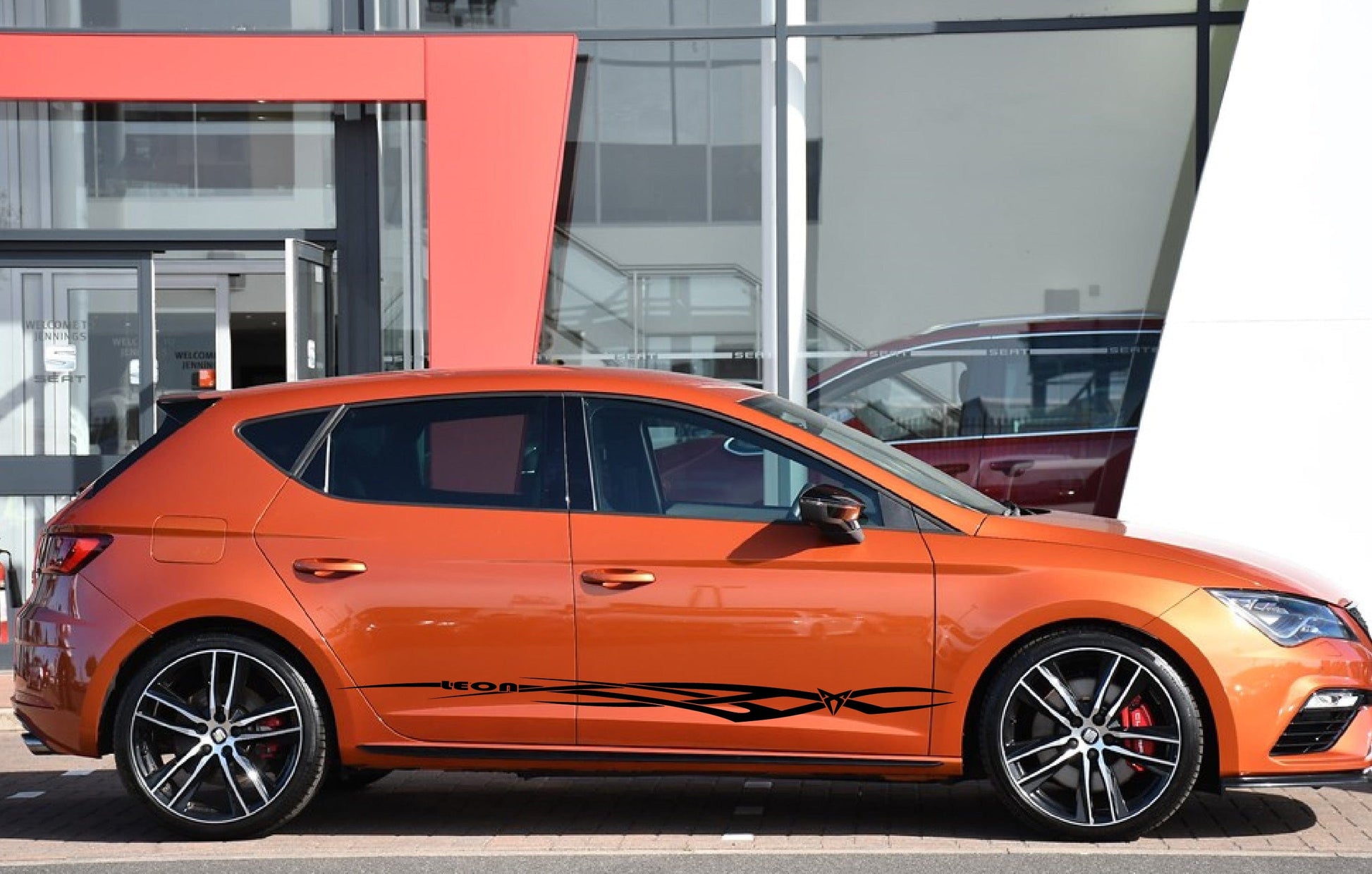 An orange Seat Leon hatchback with a set of tribal stripe premium vinyl stickers applied on the side.