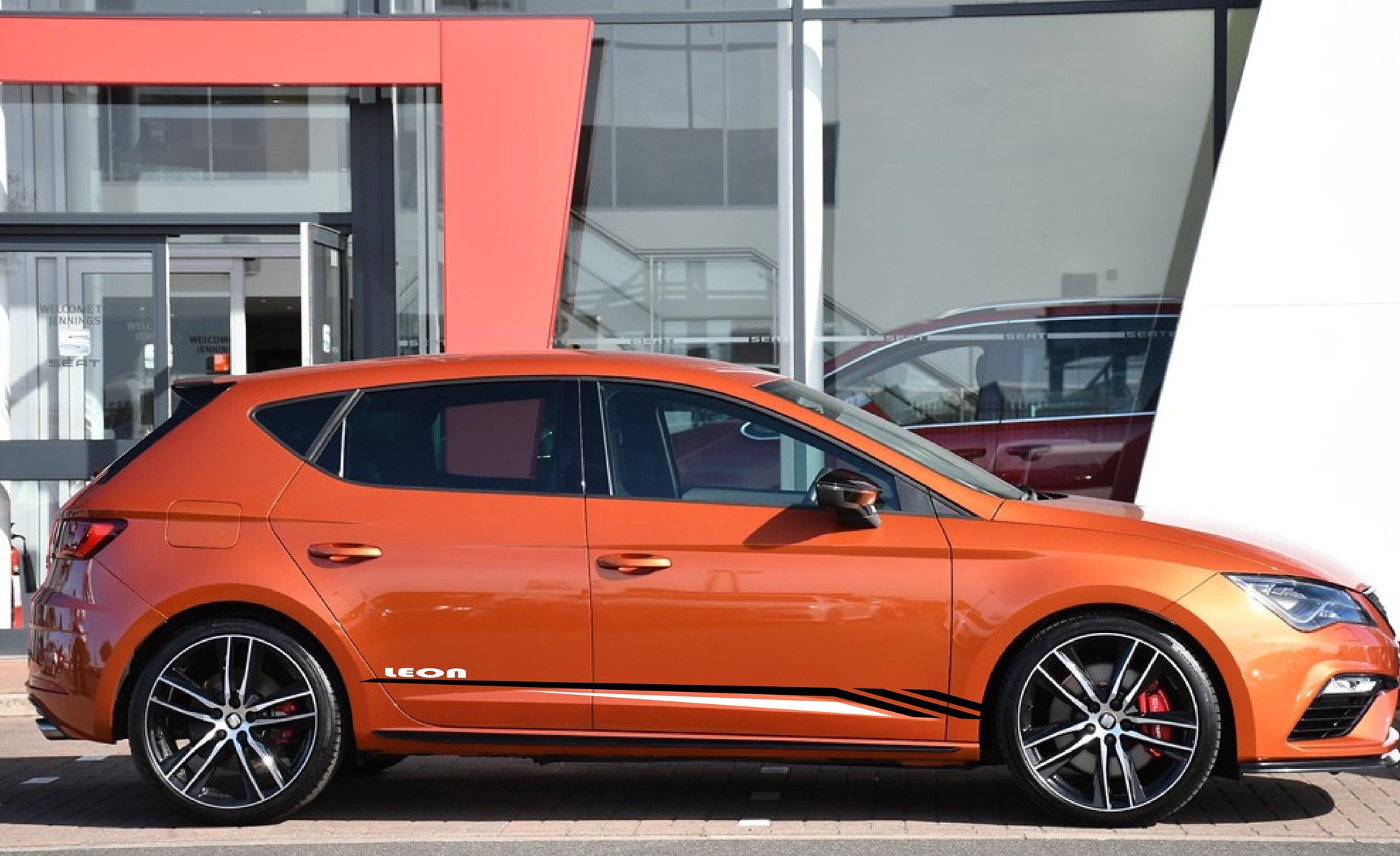 A Seat Leon vehicle with a custom vinyl decal design featuring black and white stripes on the side.