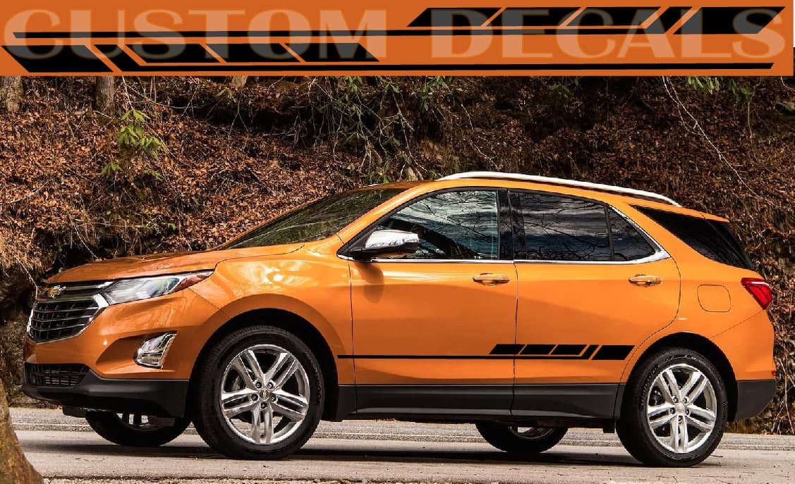 An orange Chevrolet SUV parked outdoors on a road with a rocky, wooded background. A large orange banner at the top reads 'CUSTOM DECALS' in stylized text, and black graphic decals are shown applied along the side of the vehicle.