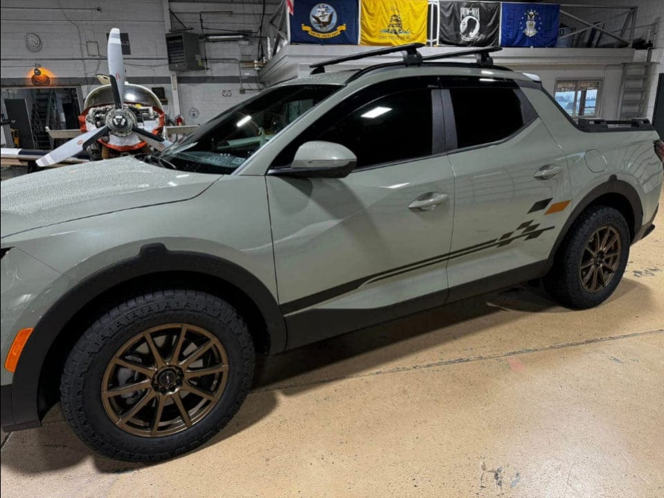 Gray SUV with off-road tires and accessories in a warehouse setting